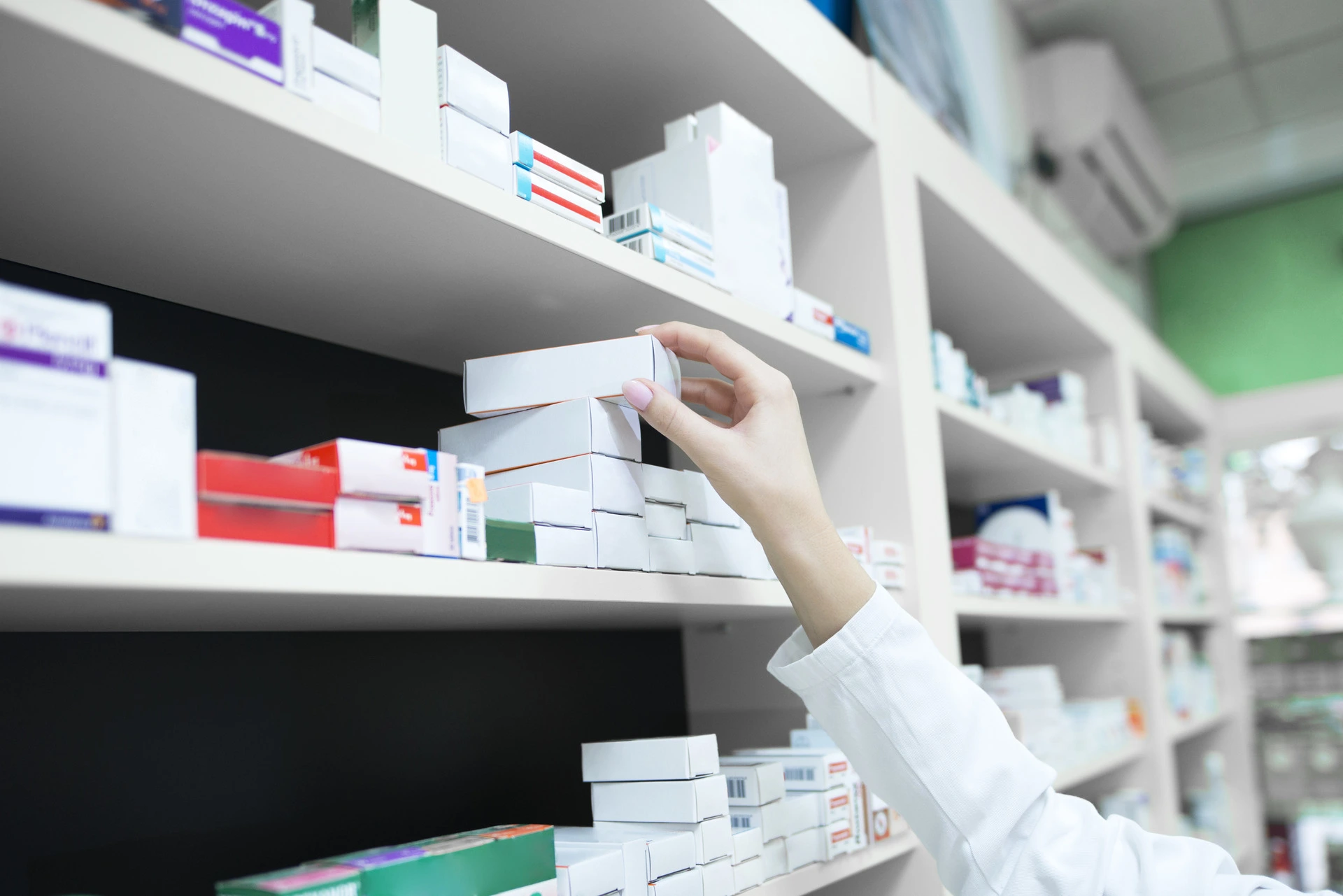 A pharmacist taking a medicine box from the dispensary shelf